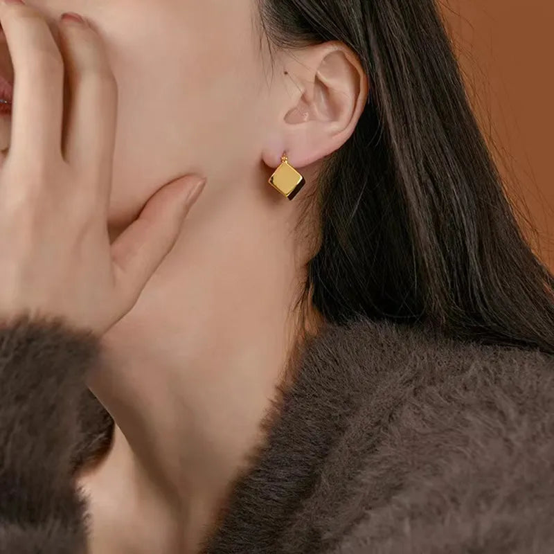 Elevate your fashion game with these exquisite gold-colored pendant earrings. Designed in a simple cubic shape, these accessories are perfect for women who want to make a statement at weddings or parties. Whether you're in Europe or America, these earrings will add a touch of elegance to your fashion style.